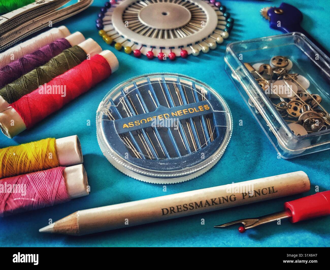 Sewing kit, Tape measure, colourful threads, pins, needles, fasteners, thimble, dressmaking pencils. High angle view Stock Photo