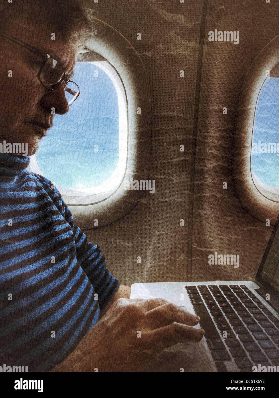 Woman on an aeroplane, working on her laptop - Smartphone Captured Stock Image