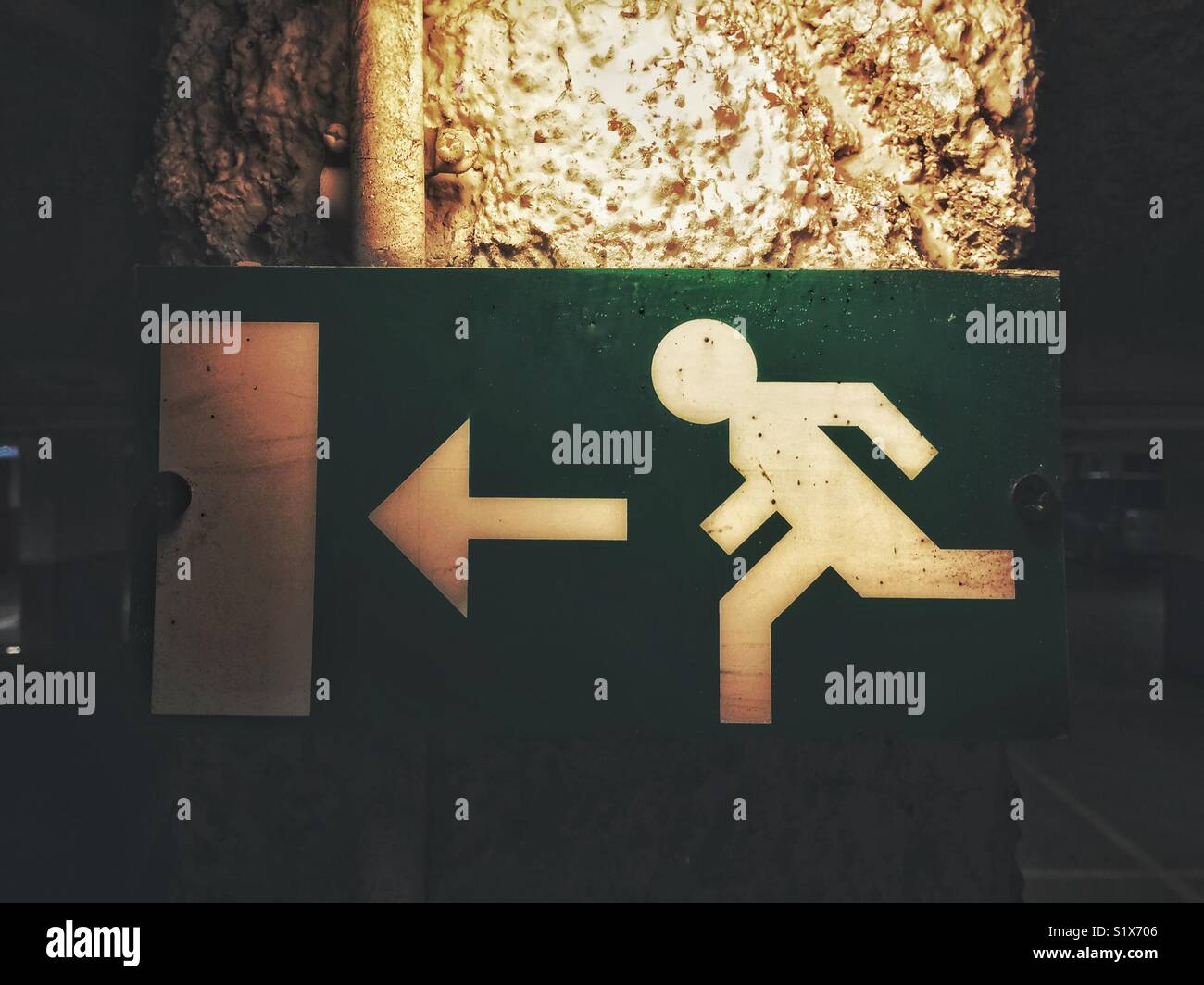 Exit sign in an underground car park with a running character and an arrow pointing to the left, France. - Smartphone Captured Stock Image