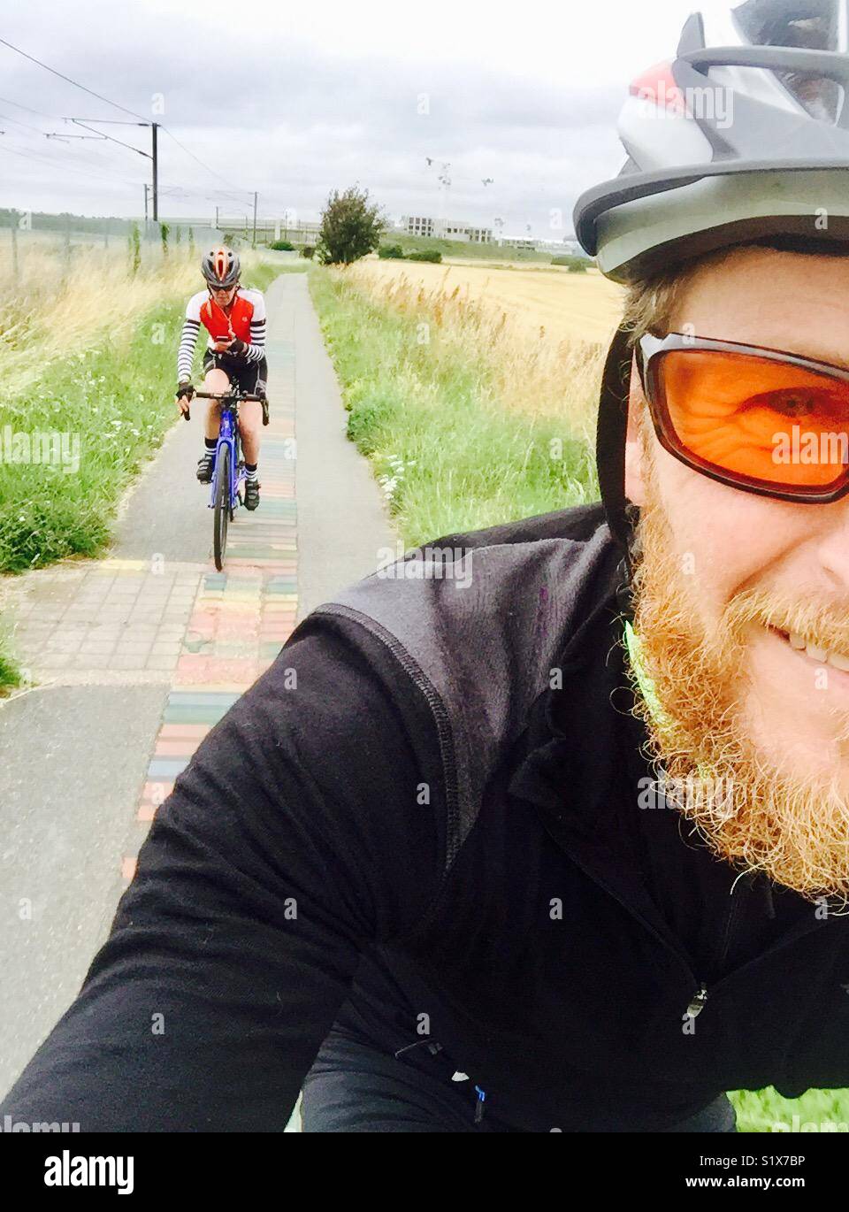 Man and woman cycling along a cycle path in England - Smartphone Captured Stock Image
