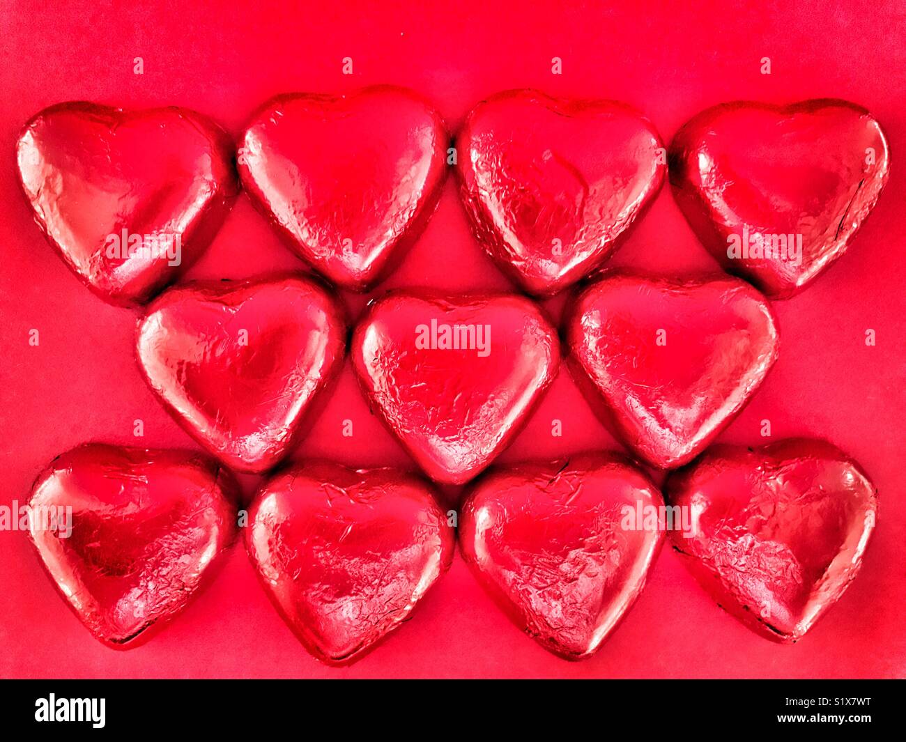 Valentine’s Day treat. Heart shaped chocolates wrapped in red foil. Flatlay photography, high angle view - Smartphone Captured Stock Image