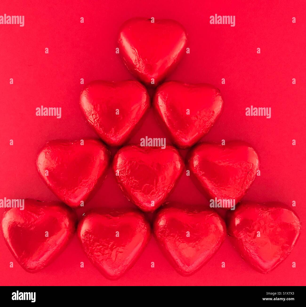 Valentine’s Day treat. Heart shaped chocolates wrapped in red foil. Flatlay photography, high angle view - Smartphone Captured Stock Image