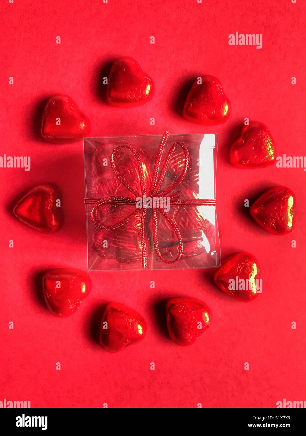 Valentine’s Day gift, Heart shaped chocolates wrapped in red foil. Flatlay photography, high angle view - Smartphone Captured Stock Image
