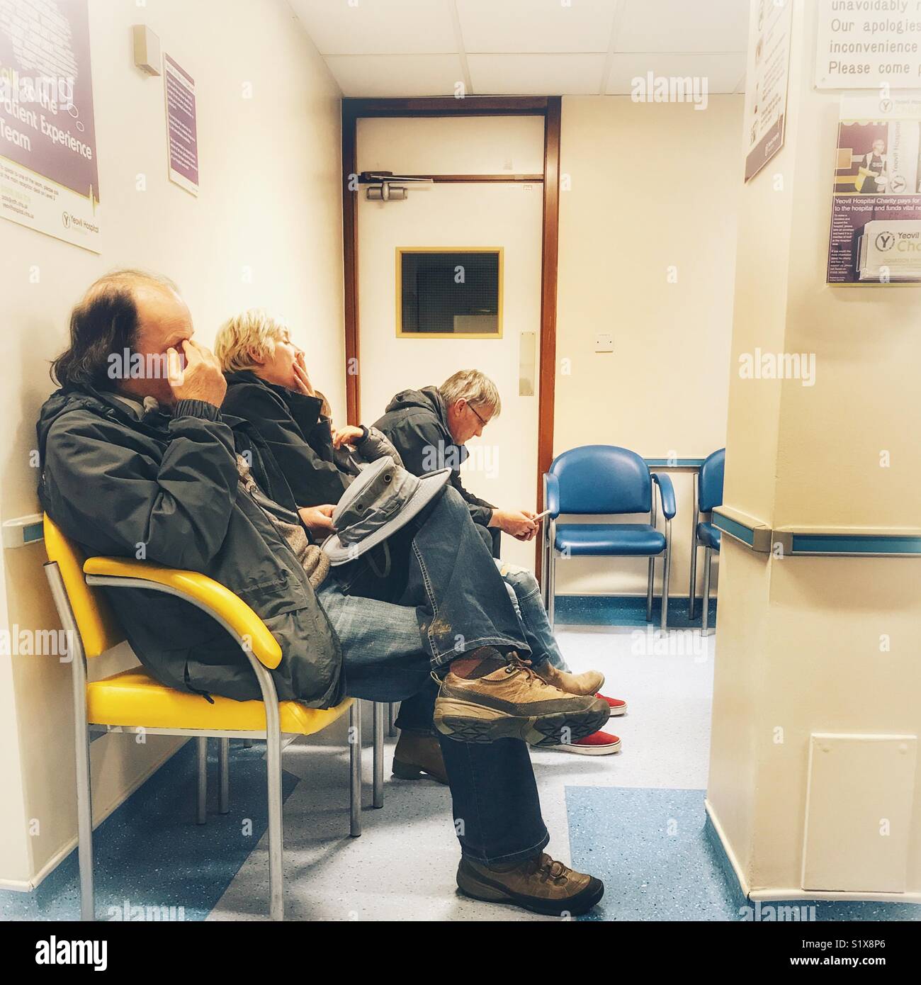 People yawning in the waiting area of an NHS Hospital, Yeovil, Somerset, England - Smartphone Captured Stock Image