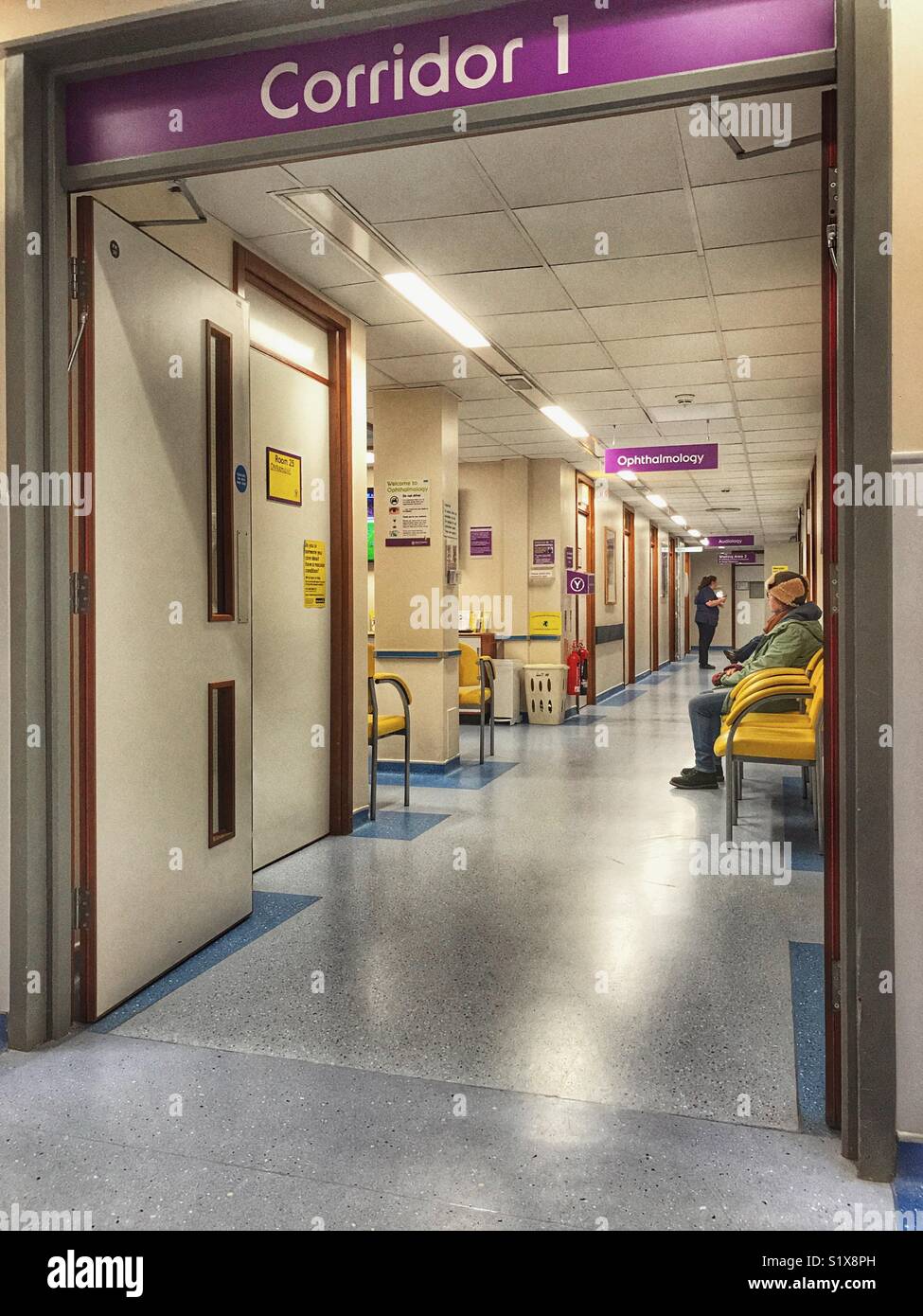 view down Corridor 1, with people waiting and a nurse beyond, the Ophthalmology Department of an NHS Hospital, Yeovil, Somerset, England - Smartphone Captured Stock Image