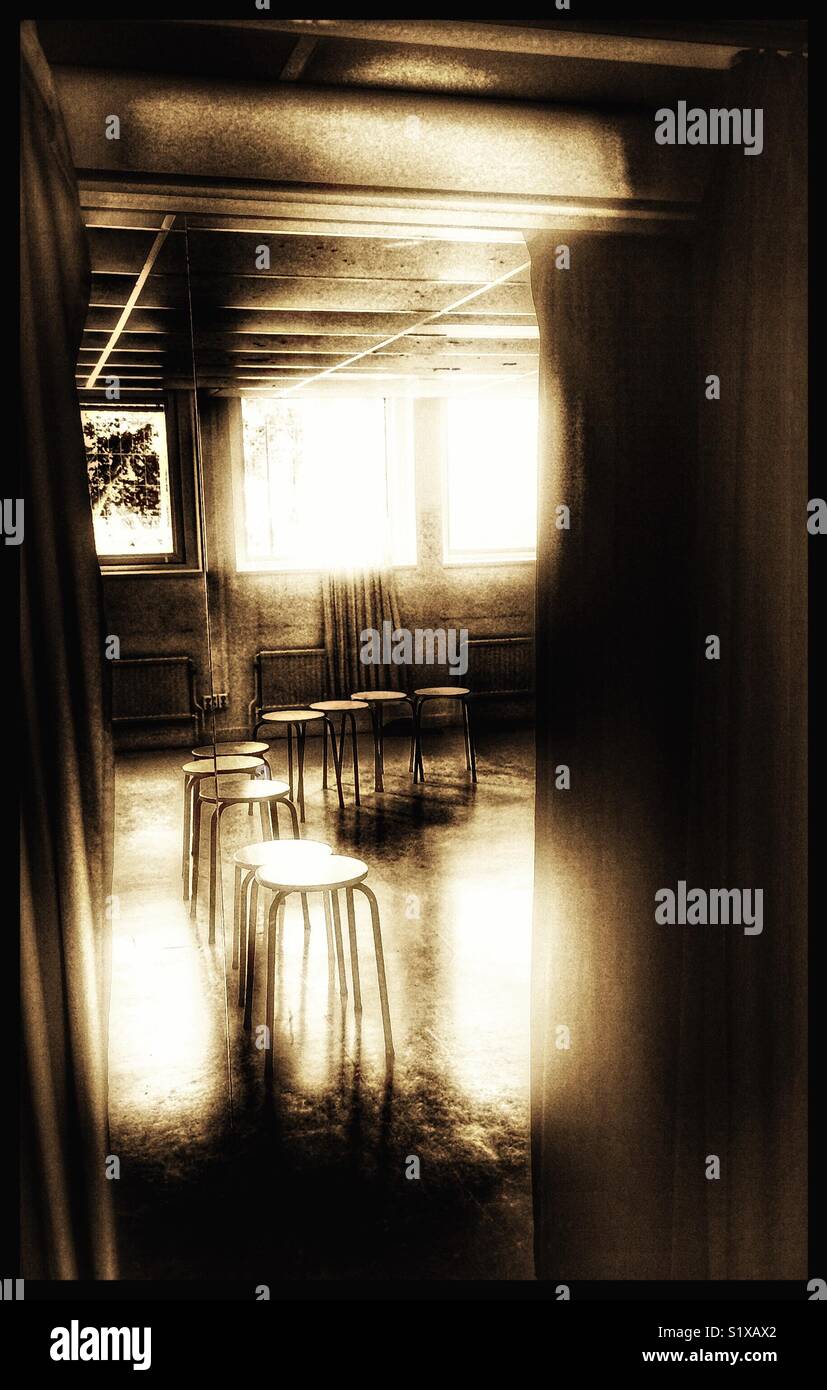 Row of empty stools reflected in mirror between curtains - Smartphone Captured Stock Image