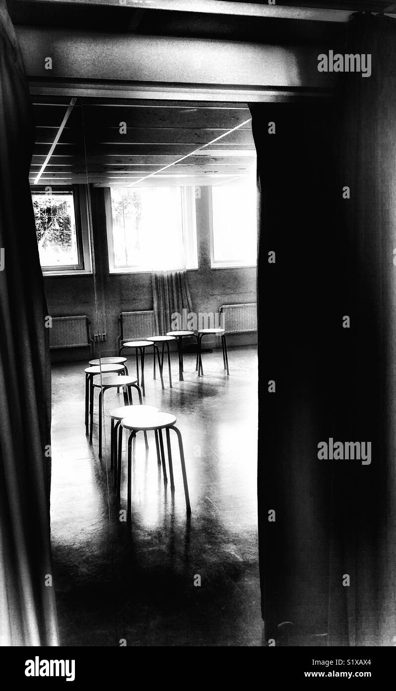 Row of empty stools reflected in mirror between curtains - Smartphone Captured Stock Image
