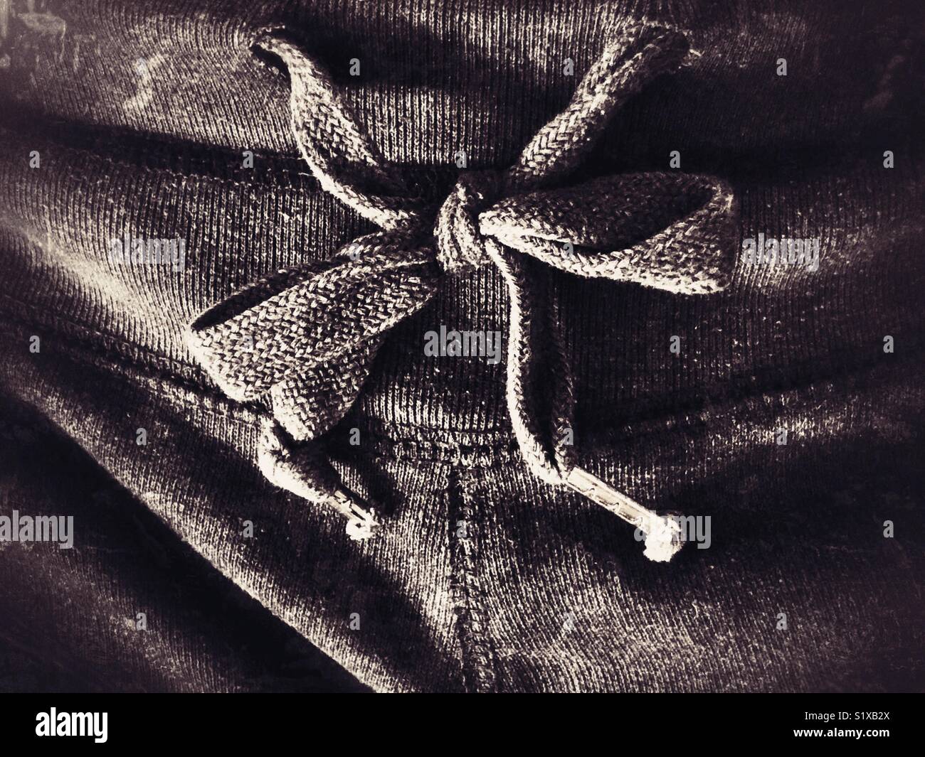 Closeup of grey fabric drawstring one sweatpants waistband loosely toed in a bow Stock Photo