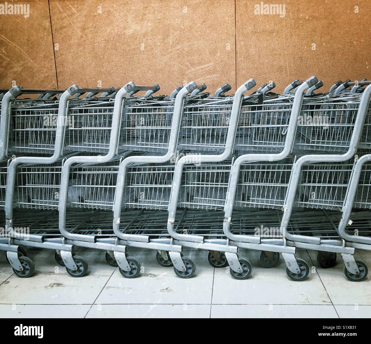 Stacked supermarket trolleys lined up against a wall - Smartphone Captured Stock Image