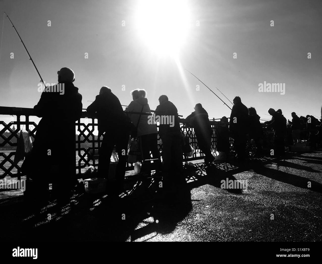 Silhouette of people fishing on Galata Bridge over the golden horn in istanbul Turkey Stock Photo