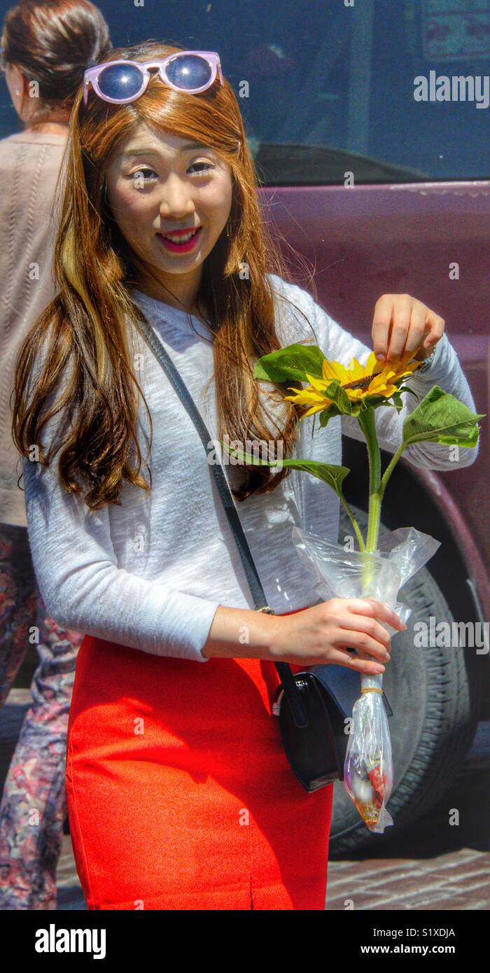 Women who just purchased a sunflower from a vendor in pikes market, Seattle Washington - Smartphone Captured Stock Image