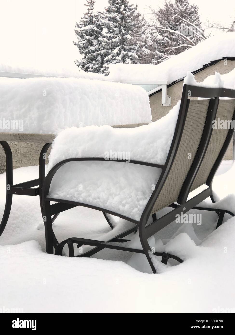 A large overnight snowfall covers patio furniture. Stock Photo