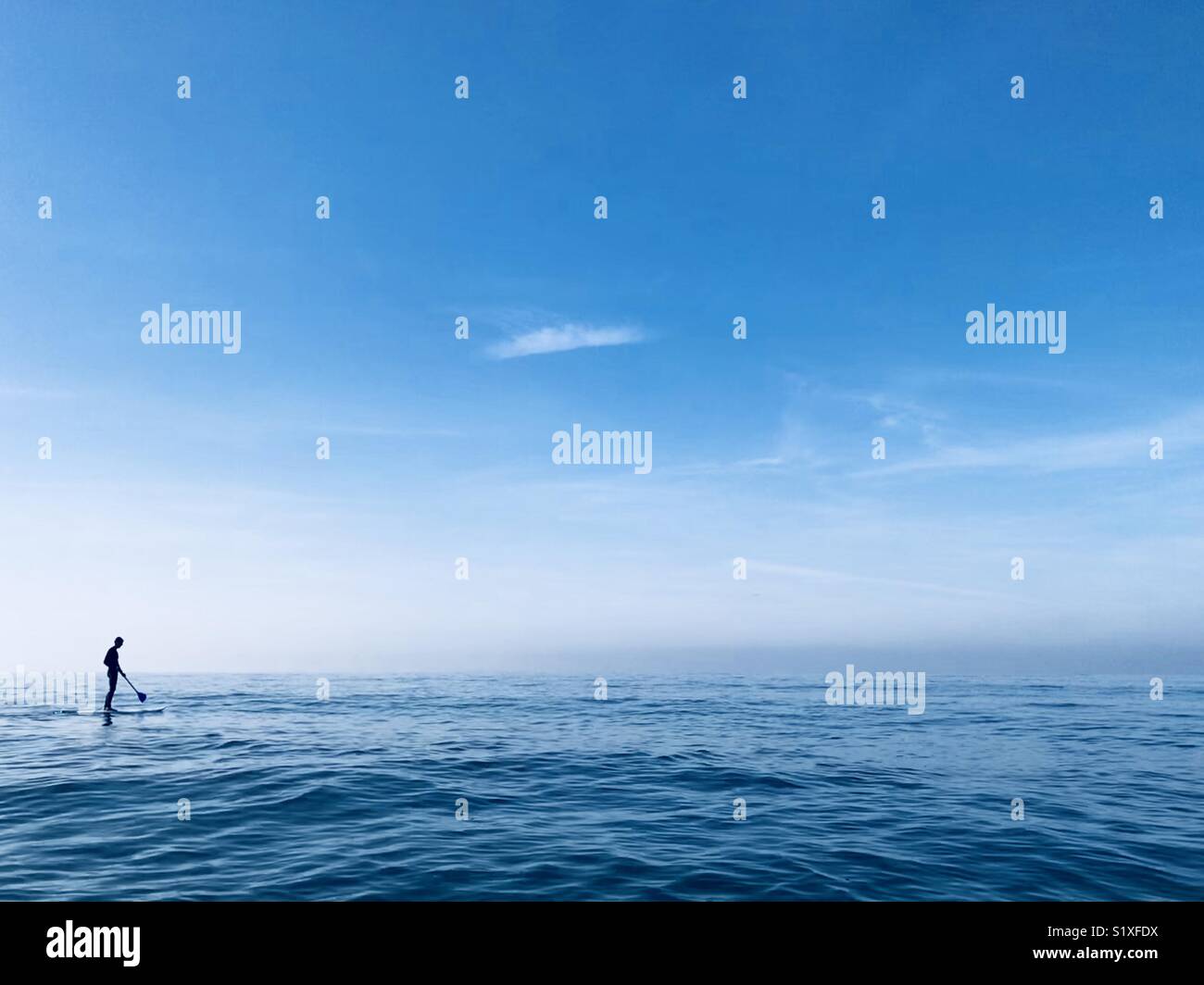 A male paddle boarder paddles in the open ocean. Manhattan Beach, California USA. Stock Photo