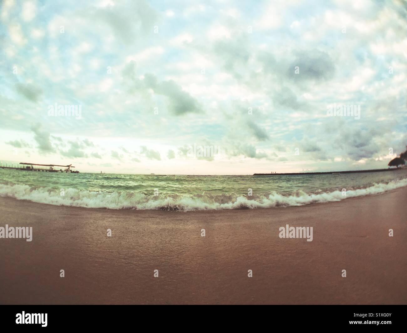 Waves of the warm Pacific Ocean breaking on the shores of a Hawaiian beach. - Smartphone Captured Stock Image