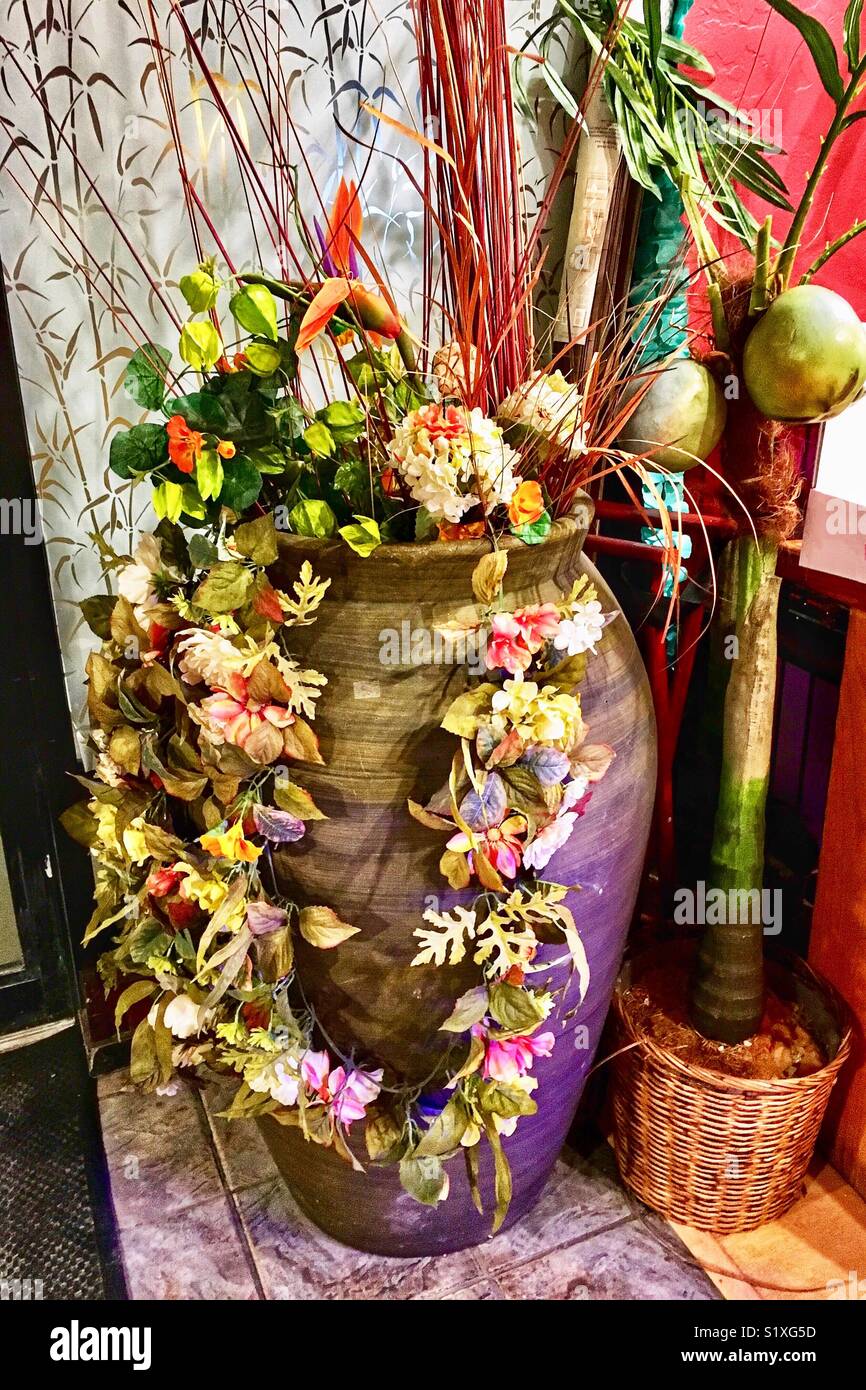 Large flower arrangement in vase and flower garland at Asian Restaurant Stock Photo