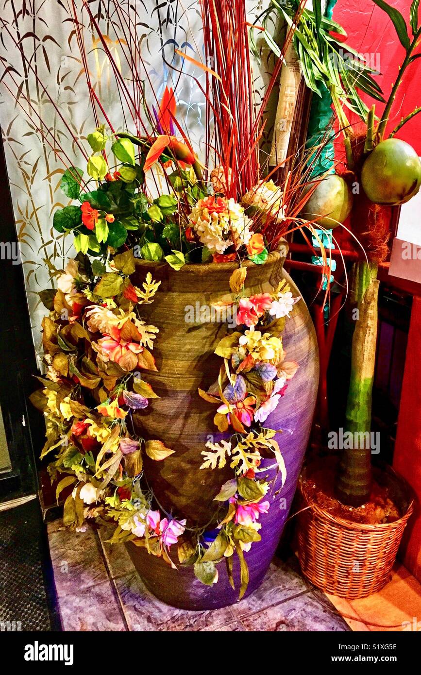 Large flower arrangement and flower garland in vase at Asian Restaurant Stock Photo