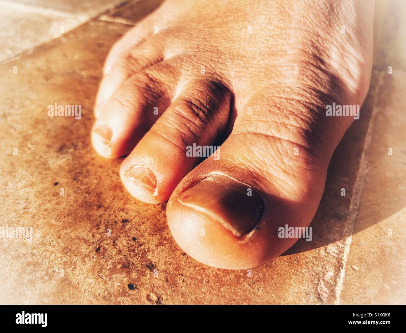 Human foot, barefoot on a terracotta floor - Smartphone Captured Stock Image