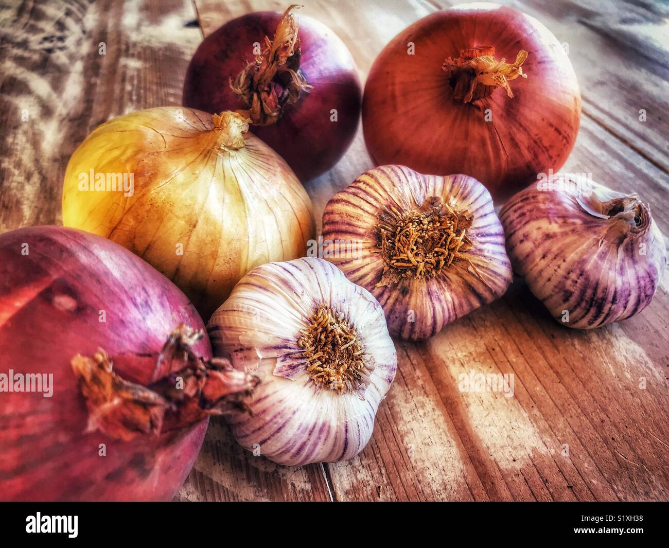 Variety of onions and garlic on a wooden table - Smartphone Captured Stock Image