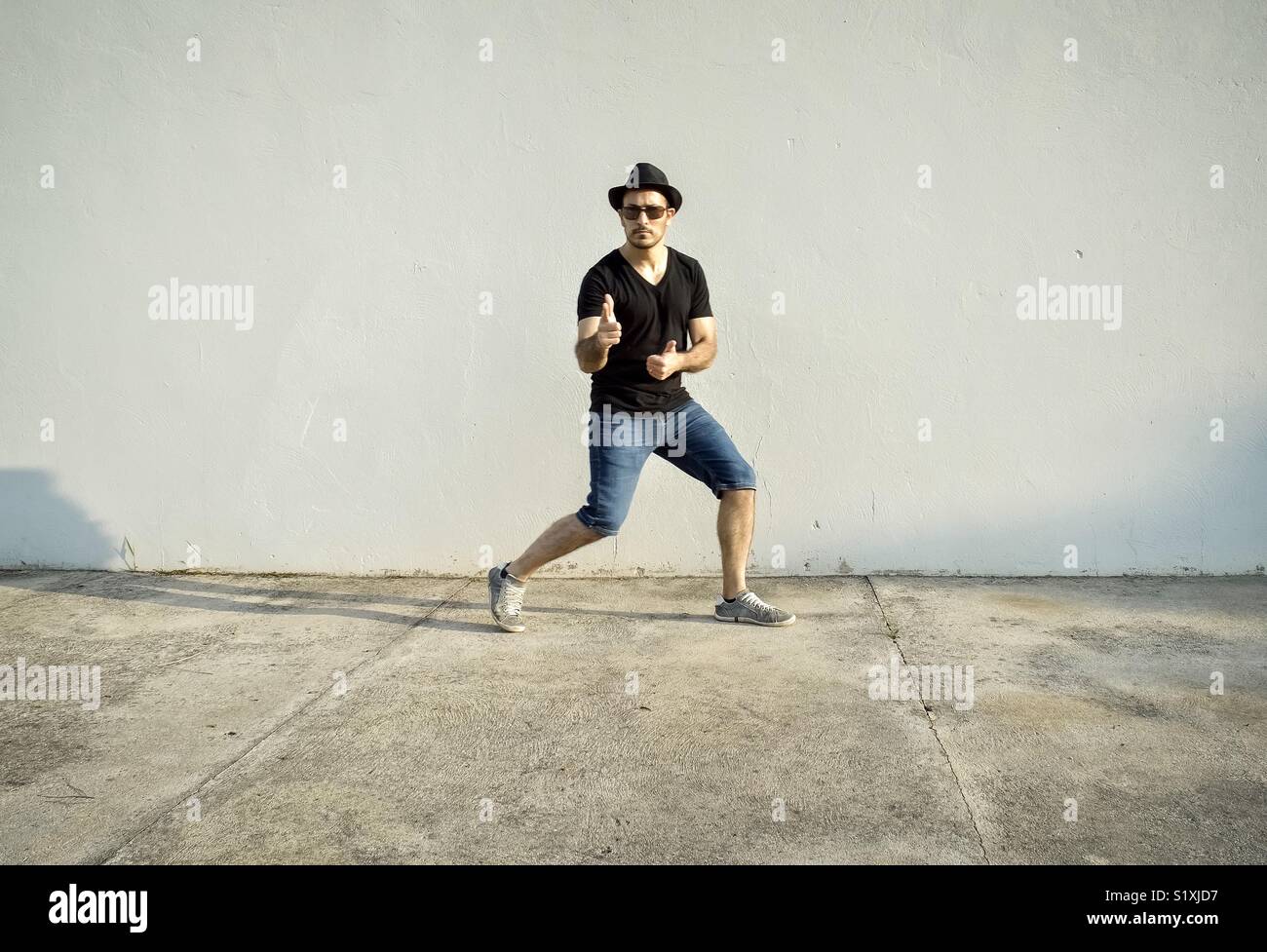 Young man against a wall and pointing to the camera - Smartphone Captured Stock Image