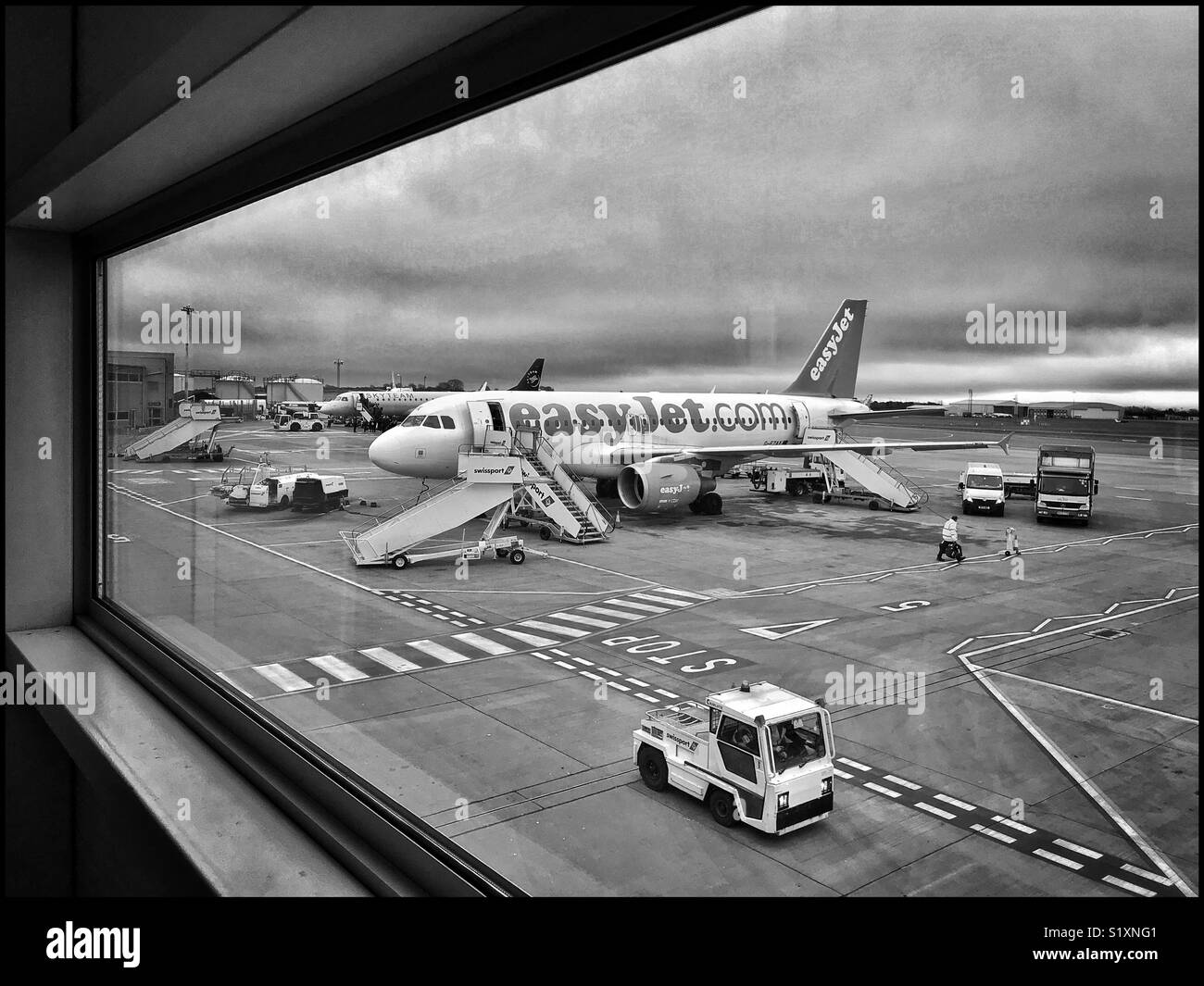 View out of a window at Bristol Airport (BRS) in England. The scene features the airside area with an EasyJet Airbus aircraft being prepared for departure. Photo Credit - © COLIN HOSKINS. Stock Photo