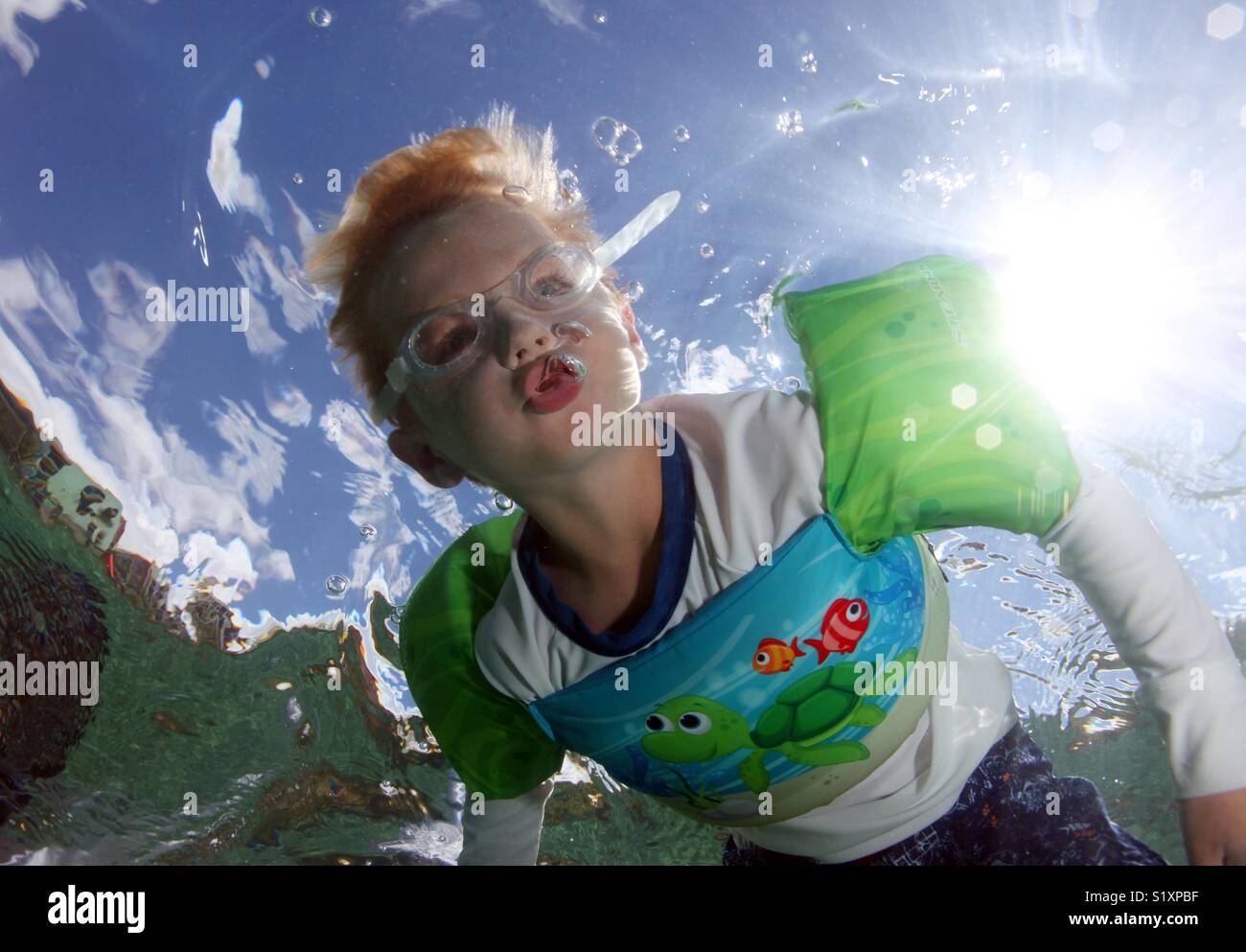 A young boy blows air bubbles underwater while snorkeling in the U.S. Virgin Islands Stock Photo