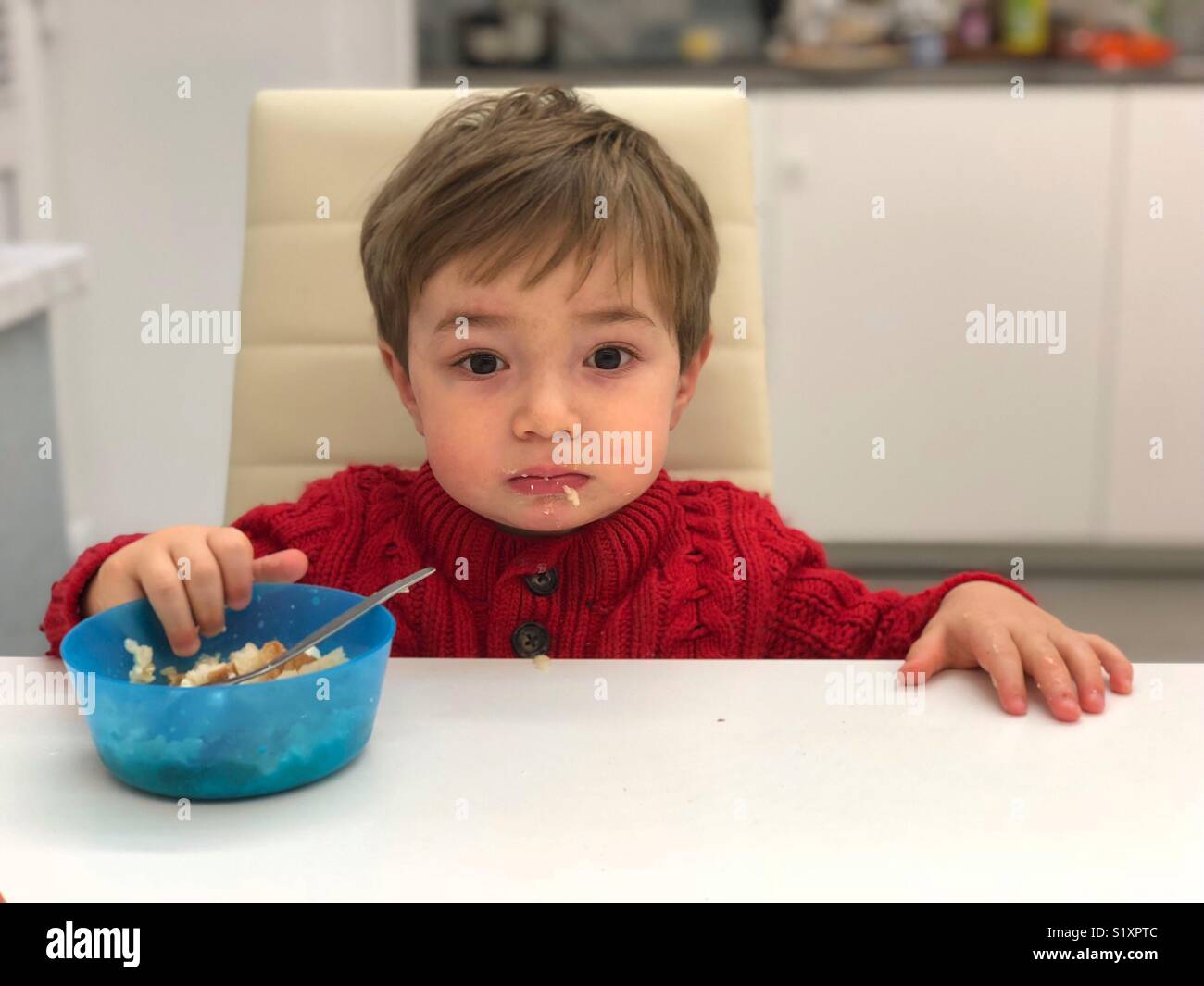 One year old baby eating by himself Stock Photo