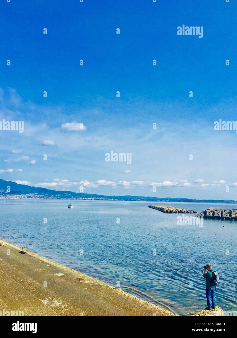 A photographer taking a photo of Beppu bay in Beppu, Japan. - Smartphone Captured Stock Image