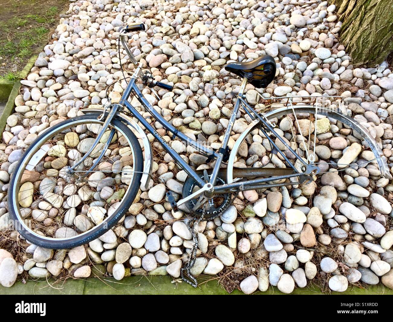 Old abandoned ladies bike with missing wheel lying on stones. Stock Photo