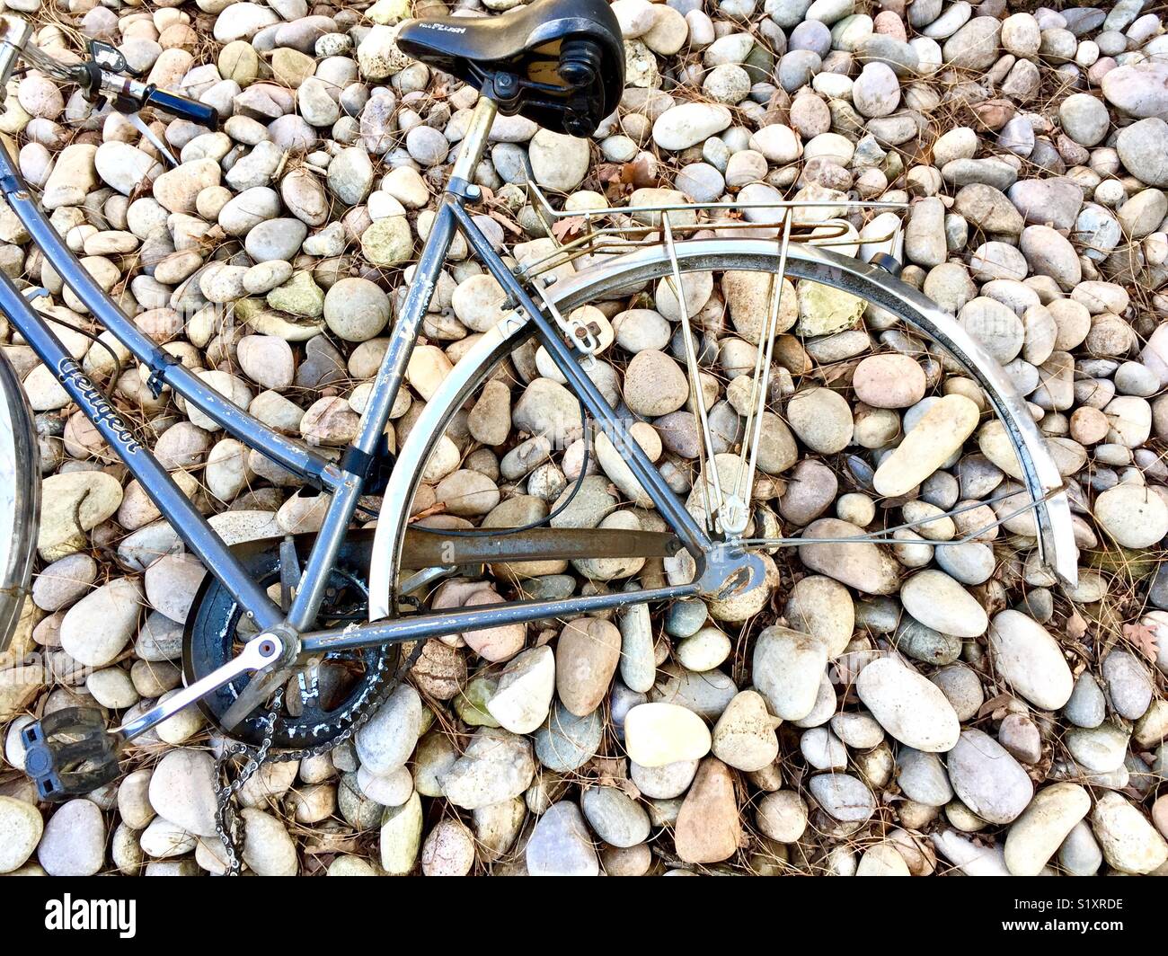 Abandoned Ladies bike with missing back wheel lying on stones Stock Photo