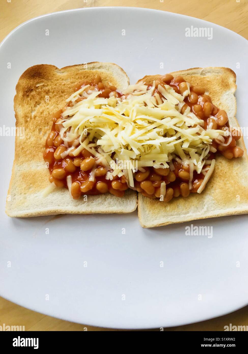 Baked beans on white toast with grated cheese Stock Photo