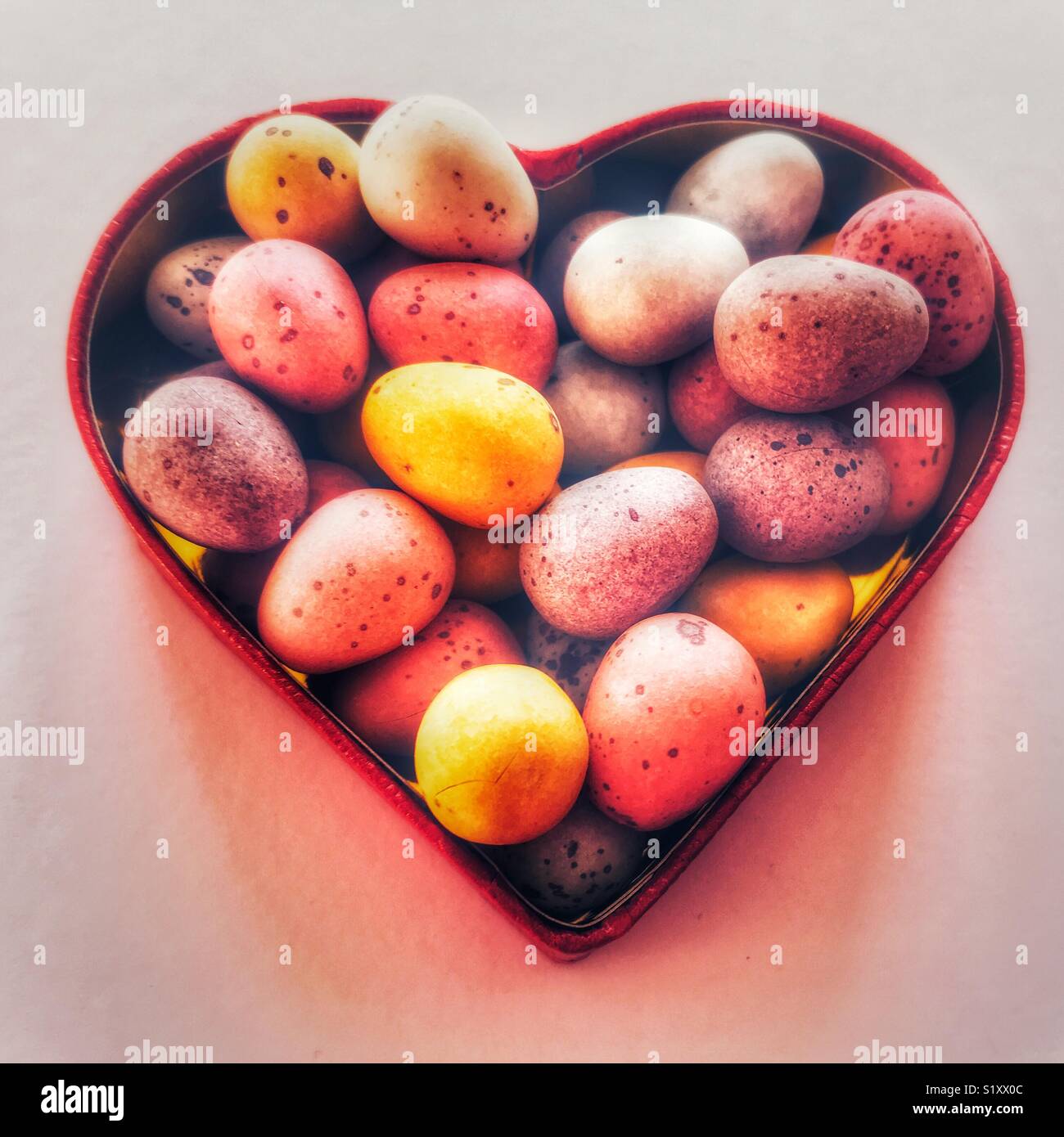 Sugar coated chocolate mini Easter eggs in a heart shaped red box - Smartphone Captured Stock Image