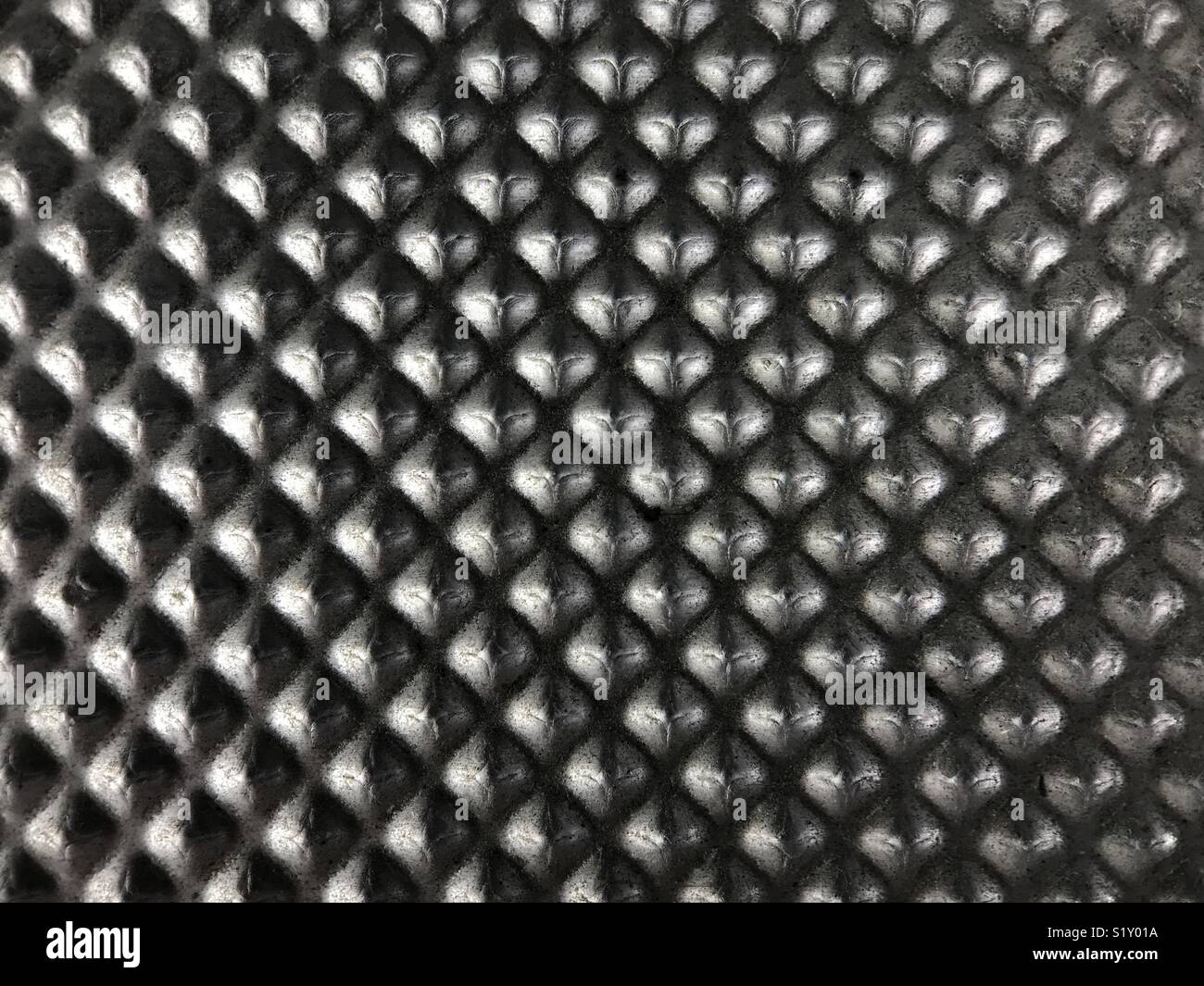 Small pyramids of a die-cast metal plate are shown up close. - Smartphone Captured Stock Image