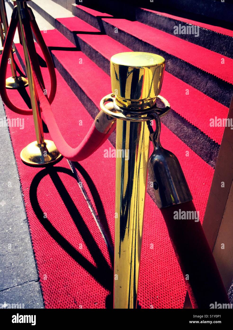 Brass stanchion and velvet ropes guard red carpet steps, USA Stock Photo
