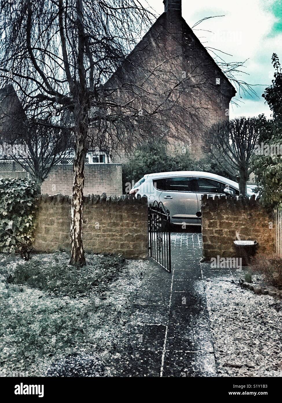 View down path to the garden gate with car beyond, on a snowy winter day in Sherborne, Dorset, England - Smartphone Captured Stock Image