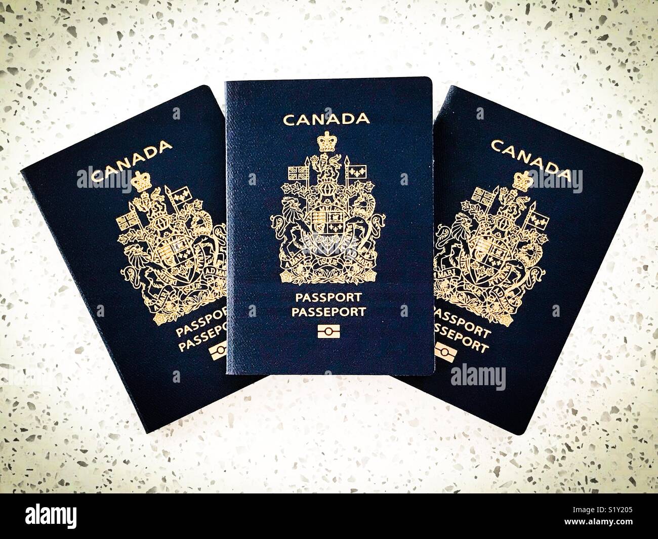 Three Canadian passports fanned out on a counter. - Smartphone Captured Stock Image