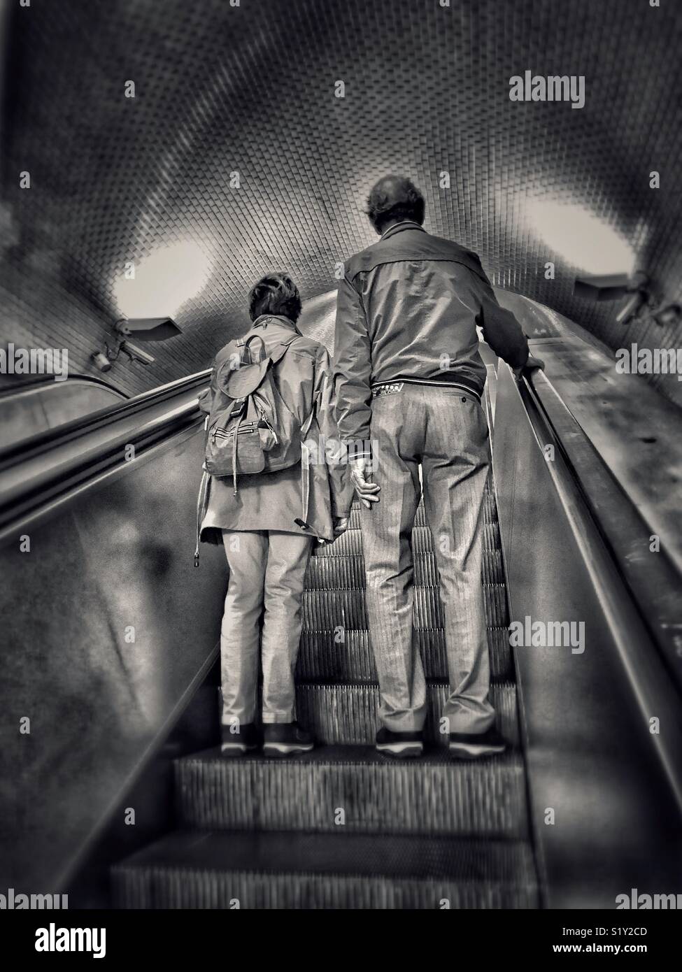 2 people - maybe married? maybe friends? - travel upwards together on an escalator. Who are they? Where are they going? Who cares? An image with multiple potential uses. Photo © - COLIN HOSKINS. - Smartphone Captured Stock Image