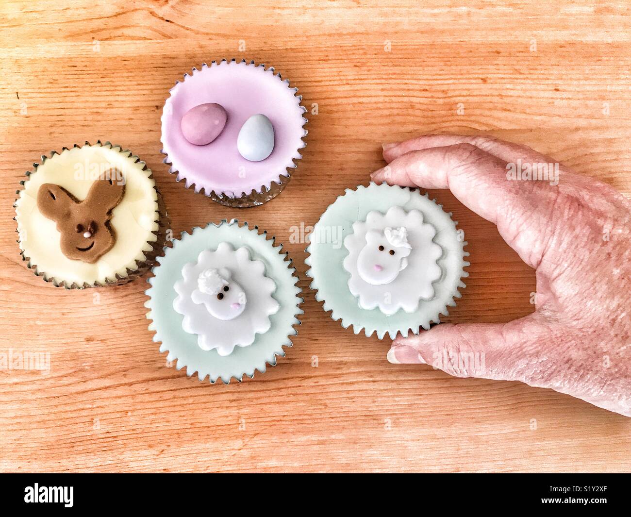 Reaching for an iced sponge cupcake, an Easter treat - Smartphone Captured Stock Image