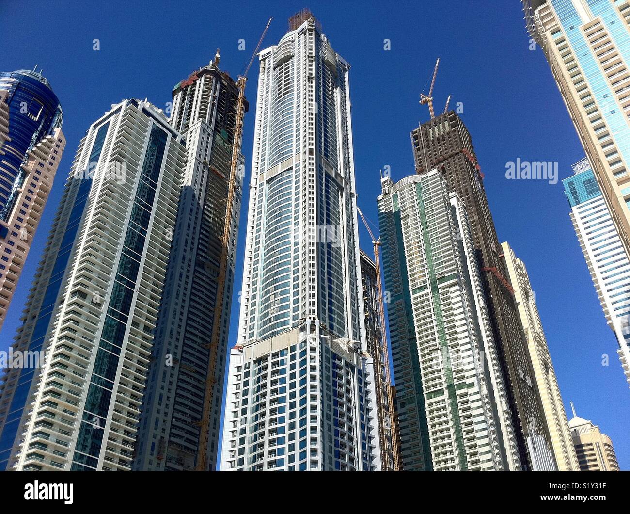 New skyscrapers being constructed in Dubai under a bright blue sky - Smartphone Captured Stock Image