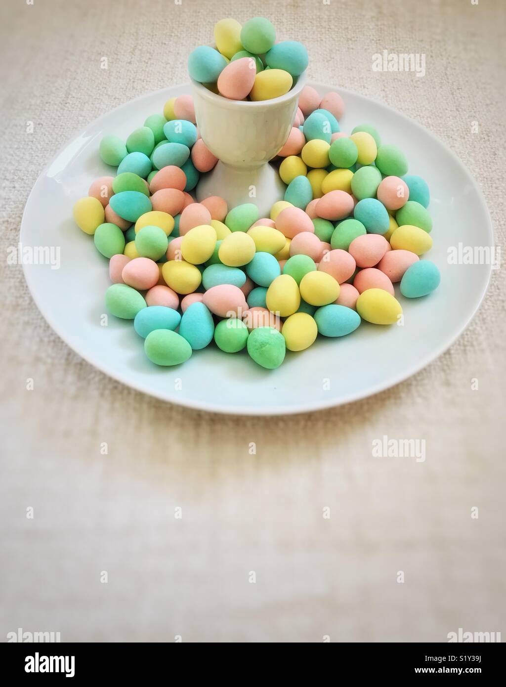 Egg cup overflowing with colourful sugar-coated chocolate mini eggs. - Smartphone Captured Stock Image
