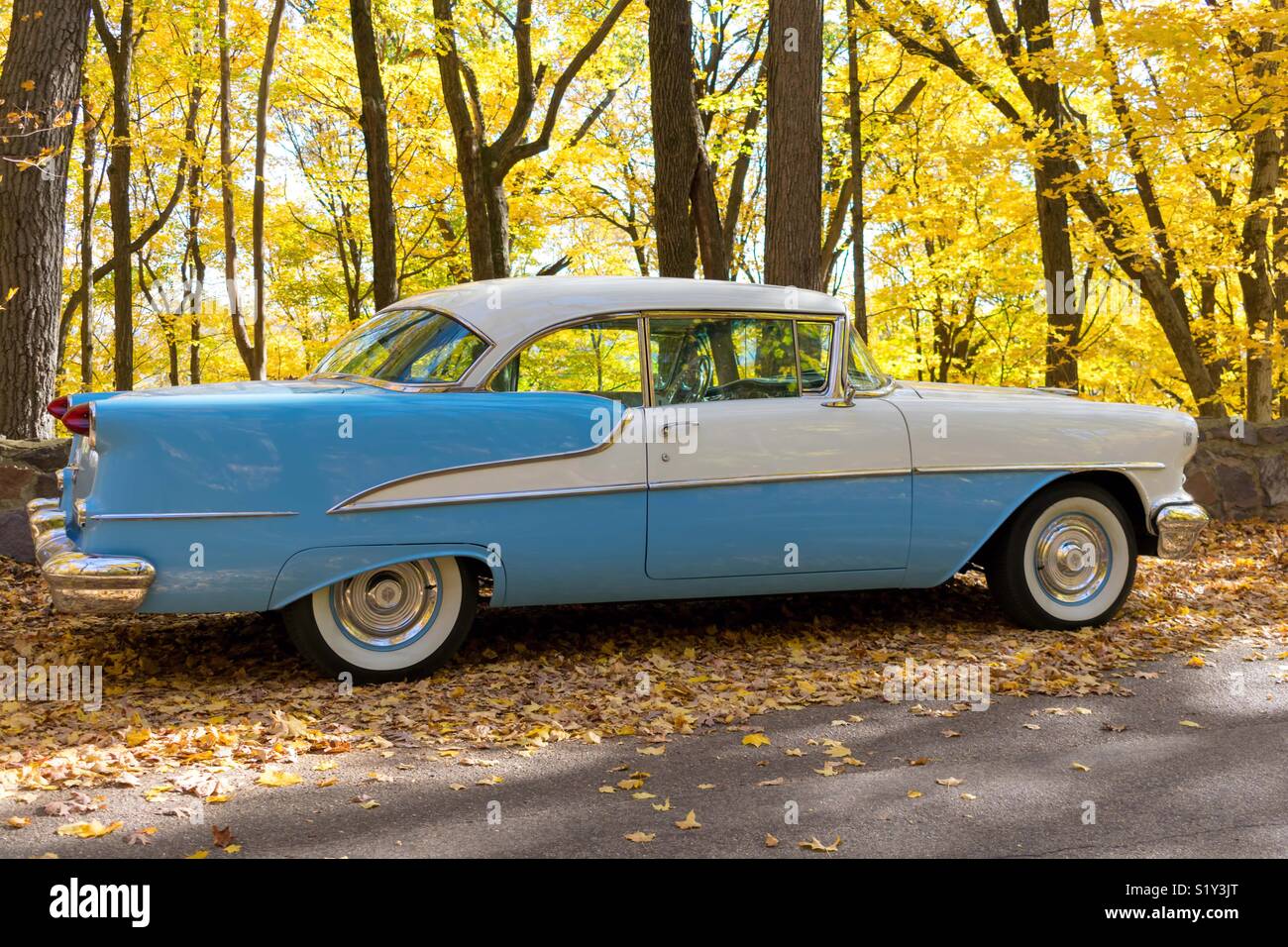 Mint condition classic car against backdrop of colorful autumn leaves Stock Photo