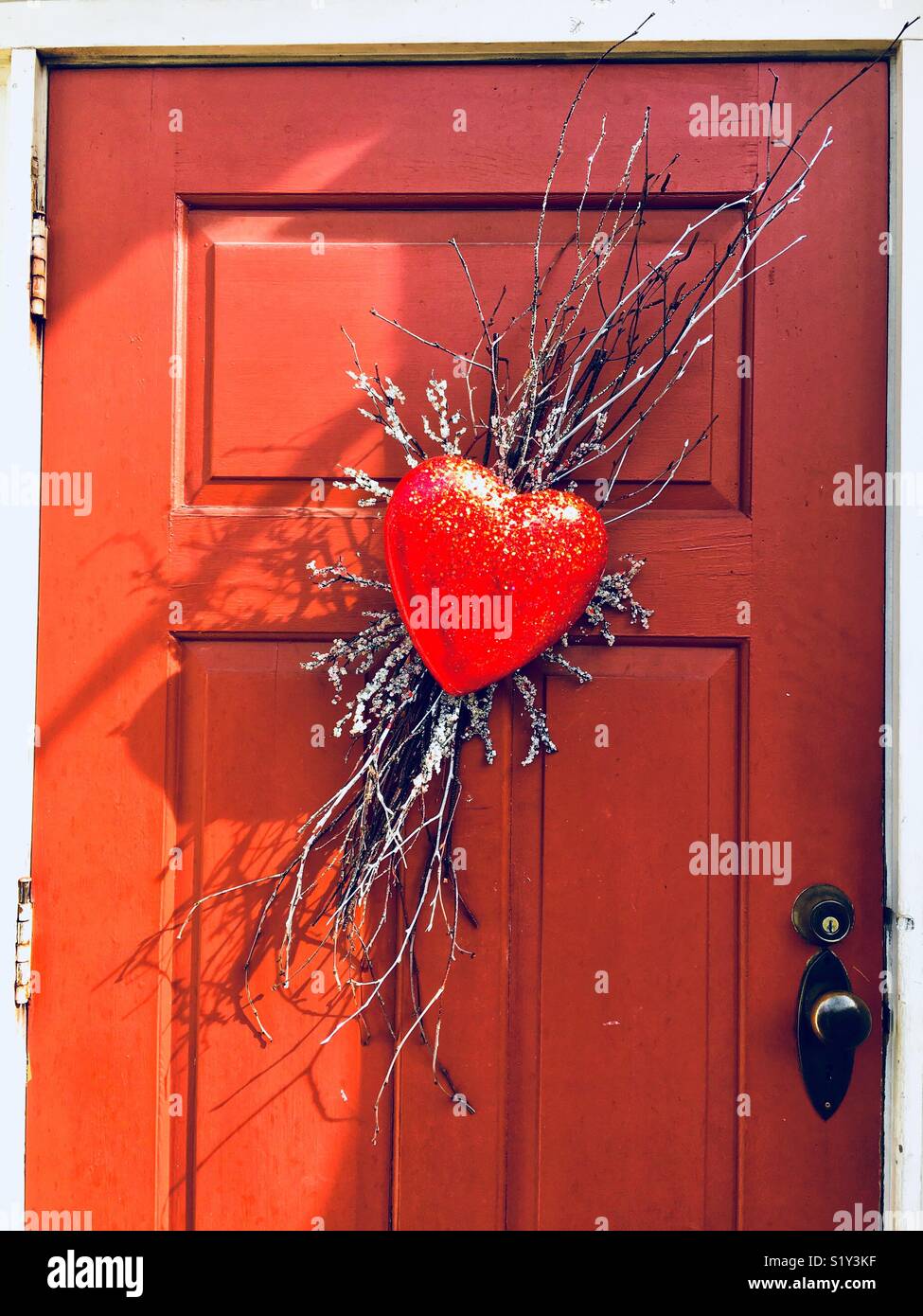 Glittery red heart wreath on orange red door - Smartphone Captured Stock Image