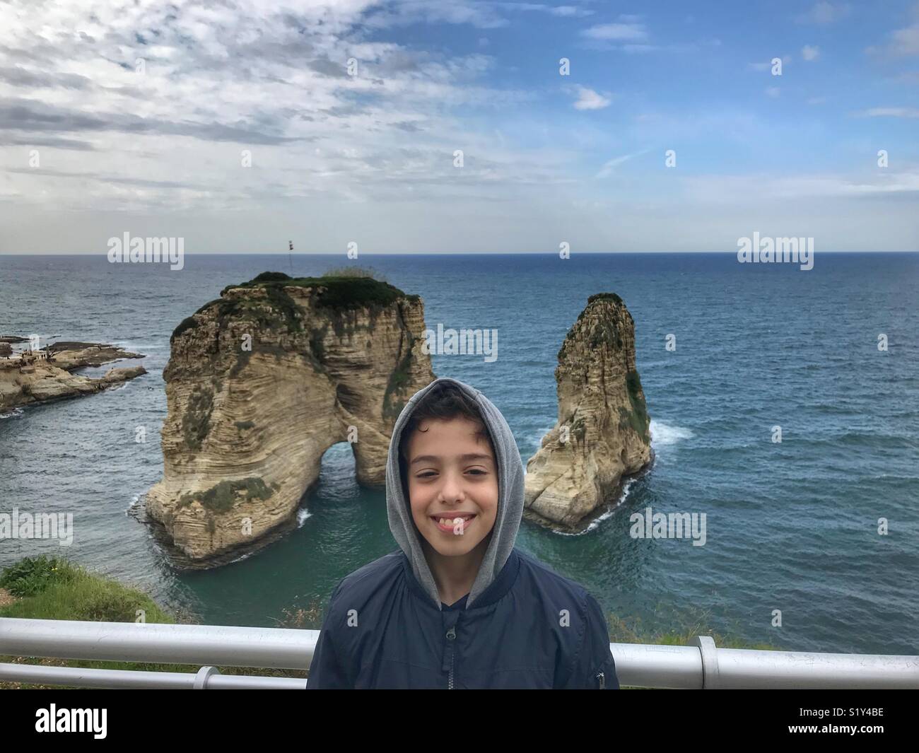 A middle eastern boy portrait with Lebanon Landmark Grand Pigeon - Rawshe in the back - Smartphone Captured Stock Image