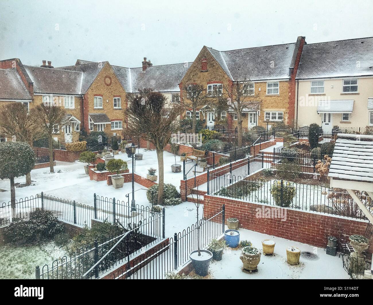 Looking out of a window onto a courtyard of gardens and residential houses during Storm Emma, a blizzard. Sherborne, Dorset, UK - Smartphone Captured Stock Image