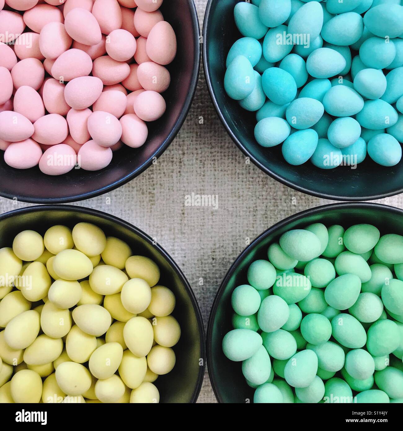 Closeup of four bowls of sugar-coated chocolate mini-eggs, separated by colour. - Smartphone Captured Stock Image