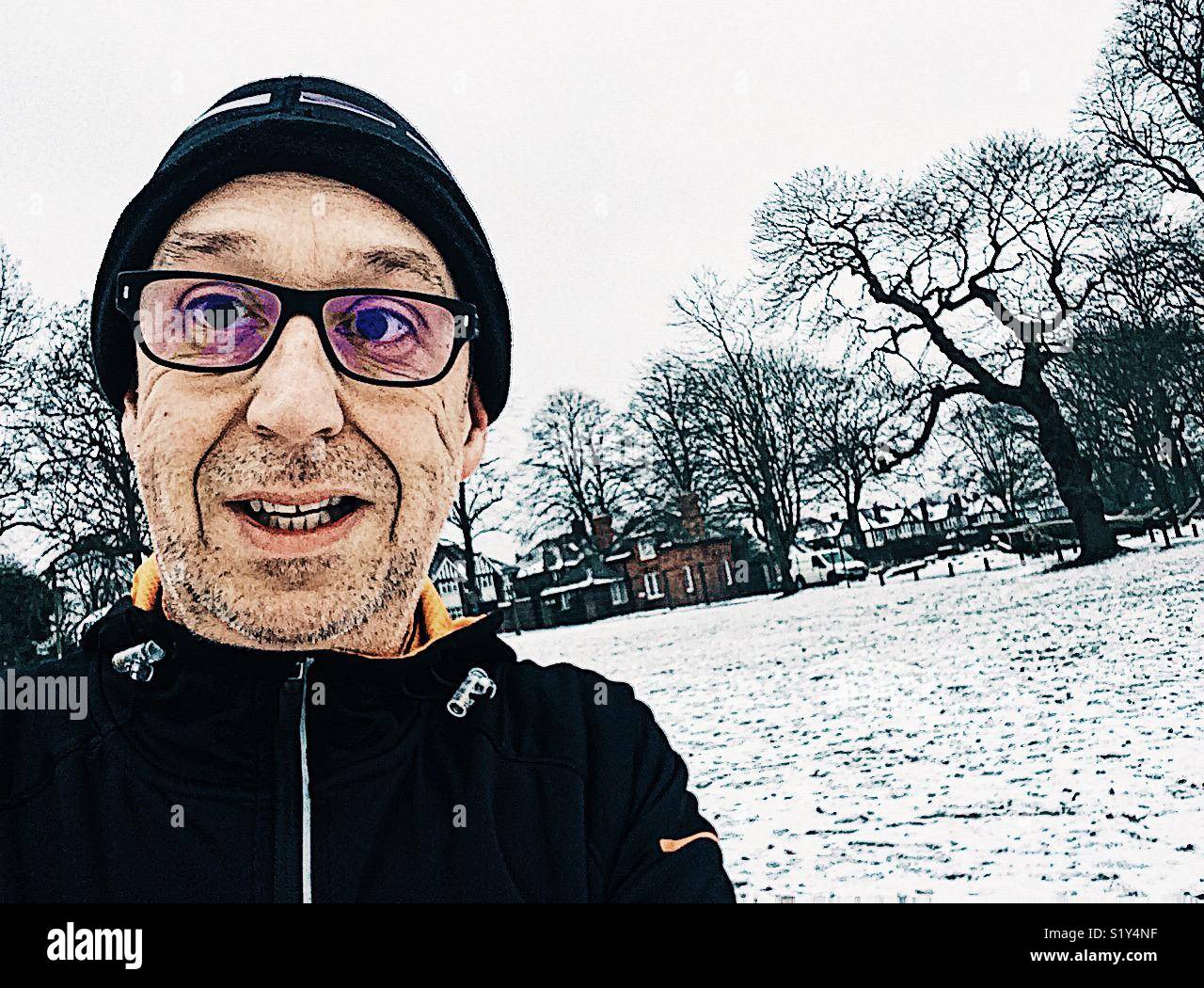 Happy middle aged man running in the snow - Smartphone Captured Stock Image