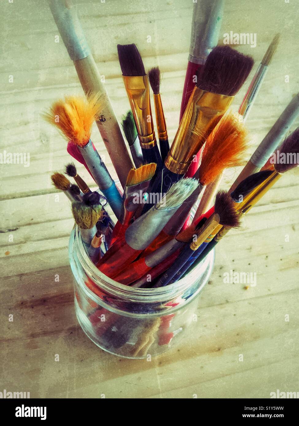 Closeup view of looking down into glass jar full of mixed art paintbrushes Stock Photo