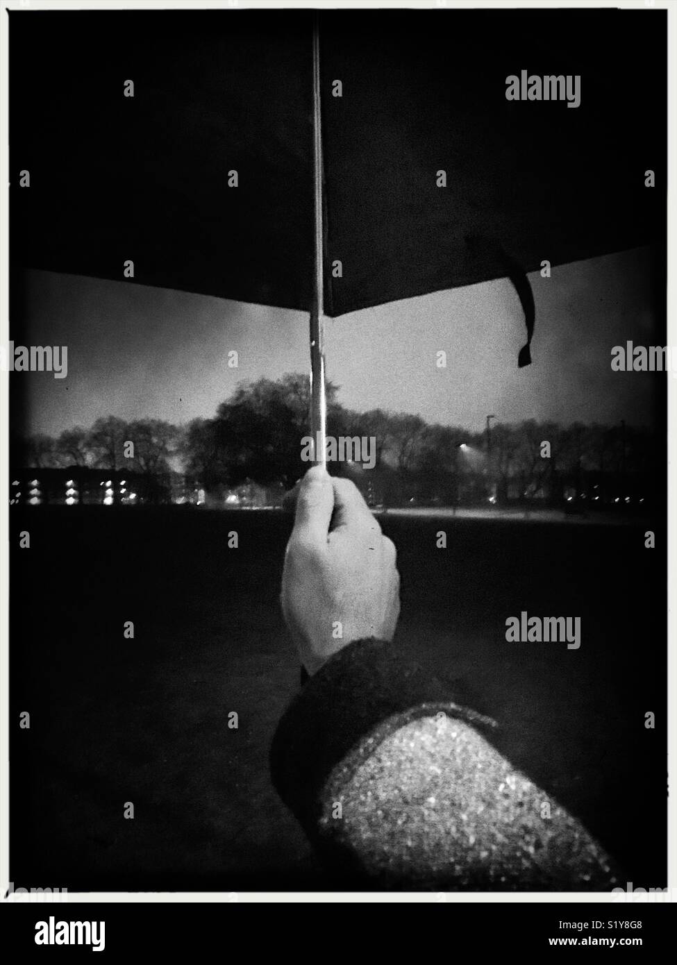 Man holding an umbrella on a rainy night - Smartphone Captured Stock Image
