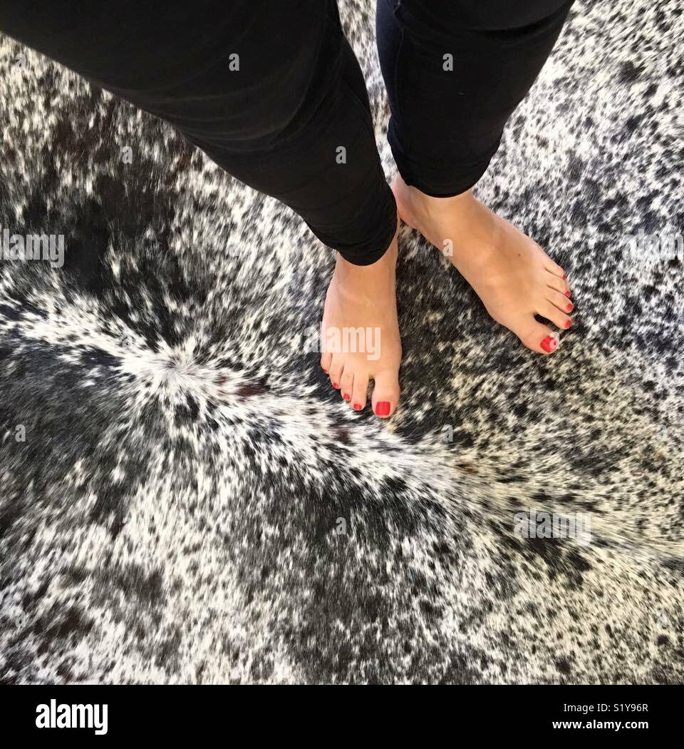 Women S Feet With Red Nail Polish On A Black White Cowhide Rug