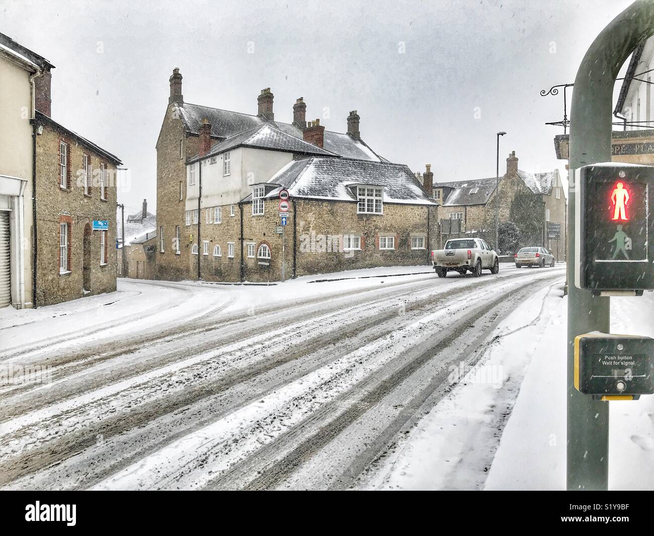 Pedestrian crossing, red man light, and view across the road during the winter blizzard, Storm Emma, March 2018. Sherborne, Dorset, England - Smartphone Captured Stock Image