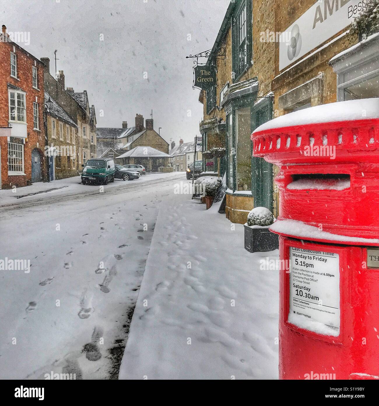Winter townscape and a red post box with heavy snowfall in Sherborne, Dorset, England during the blizzard of Storm Emma, March 2018 - Smartphone Captured Stock Image